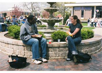 two people conversing by a campus fountain