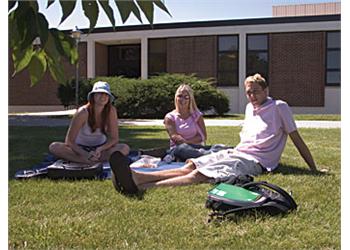 three students lounging on campus grounds