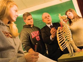 three students and teacher discussing over books