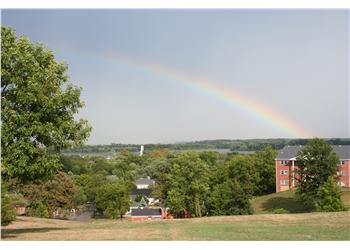 rainbow over campus buildings and trees