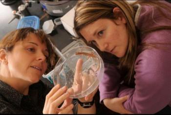 two people examining a petri dish in a lab setting