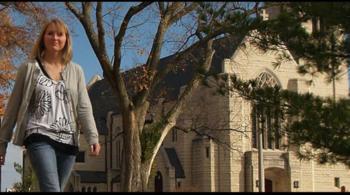 student walking by campus stone buildings in autumn