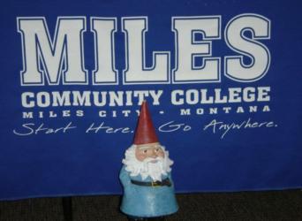 gnome figurine in front of 'miles community college miles city - montana' banner