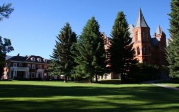 historic building with spire behind tall trees on a sunny day