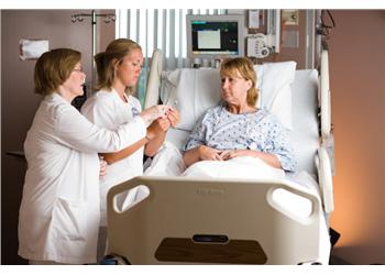 two nurses with patient in hospital bed