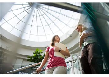 two women conversing in a bright atrium