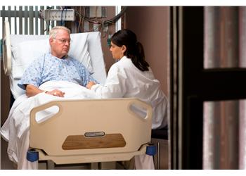 nurse conversing with patient in bed