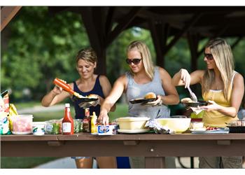 three women serving food at picnic