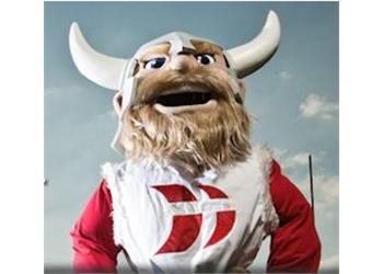 mascot in red attire with horns against a sky backdrop