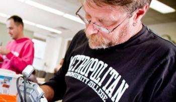 man in 'metropolitan community college' t-shirt working on equipment