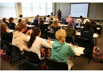 lecture with students taking notes from a projection