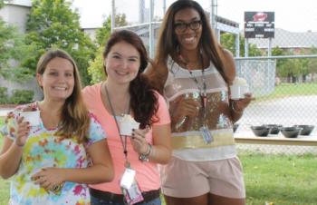 three students holding coffee cups