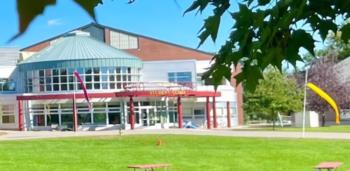 green lawn in front of a campus building with red awning