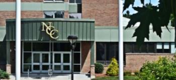 entrance of a building with 'ncc' logo and greenery