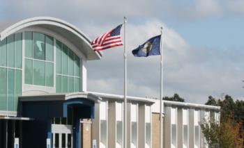 american and state flag in front of a building with arched roof