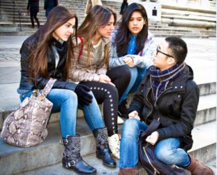 four students sitting and chatting on steps outdoors