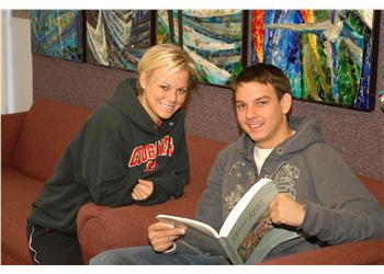 two students smiling with book and 'auburn u.' hoodie