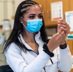 student in lab with syringe and mask