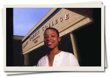 person smiling in front of 'first county college' signage