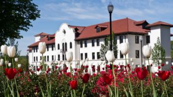 white building with red roof behind tulips