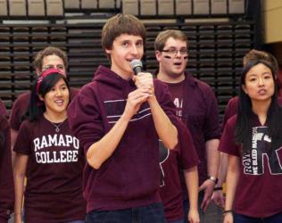 students in 'Ramapo College' shirts singing at an event