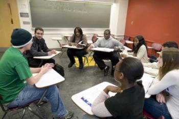 students in a circle discussion in front of a chalkboard