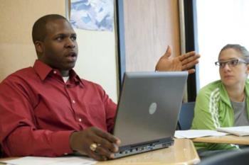 a man presenting at a laptop with a colleague beside him