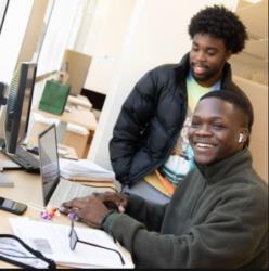 two students smiling at computer desk