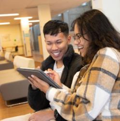 two students looking at tablet and smiling