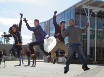 students jumping in front of a campus building