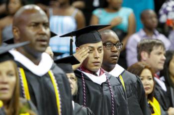 graduates in robes saluting at ceremony