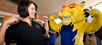 woman smiling next to mascot in lion costume