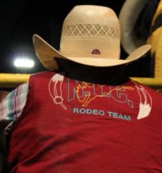 person in hat with 'ngc rodeo team' shirt at night