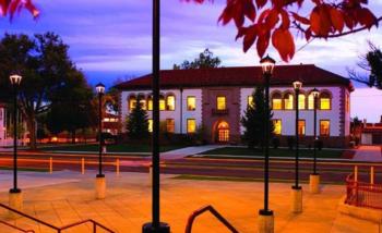 twilight view of historic building with lamps and trees