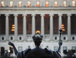 statue silhouette with lit building in background