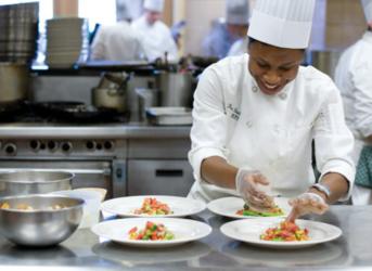 chef garnishing plates in a commercial kitchen