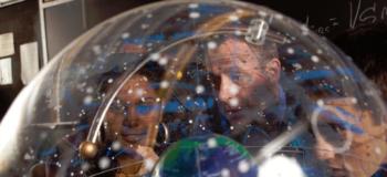 two people looking at a globe through a transparent sphere