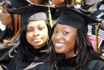 two graduates smiling in black caps and gowns