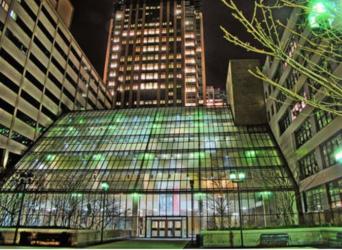 illuminated glass building at night with surrounding structures