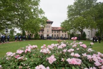 campus building with students and blooming flowers in foreground