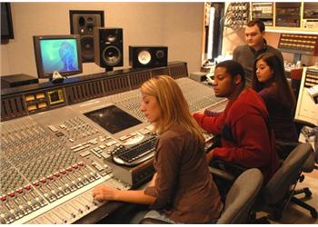 students at a sound mixing board in a studio