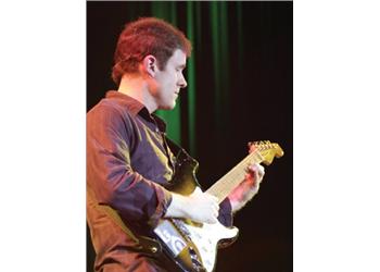 guitarist performing on stage in blue light