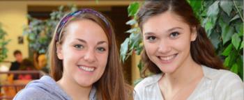 two smiling female students posing indoors