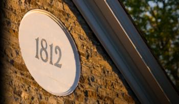 '1812' sign on brick wall at dusk