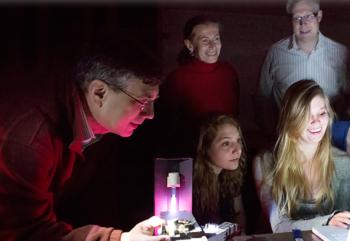 man demonstrating to audience with purple light in dark room