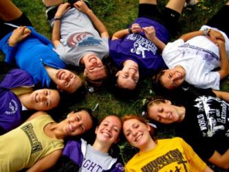 circle of students lying on grass heads together