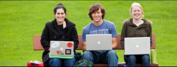 three students with laptops sitting on a bench