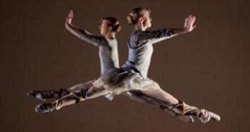 two dancers in mid-air performing a leap