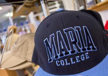 close-up of a black cap with 'maria college' embroidered