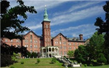 historic brick building with a clock tower and manicured lawn